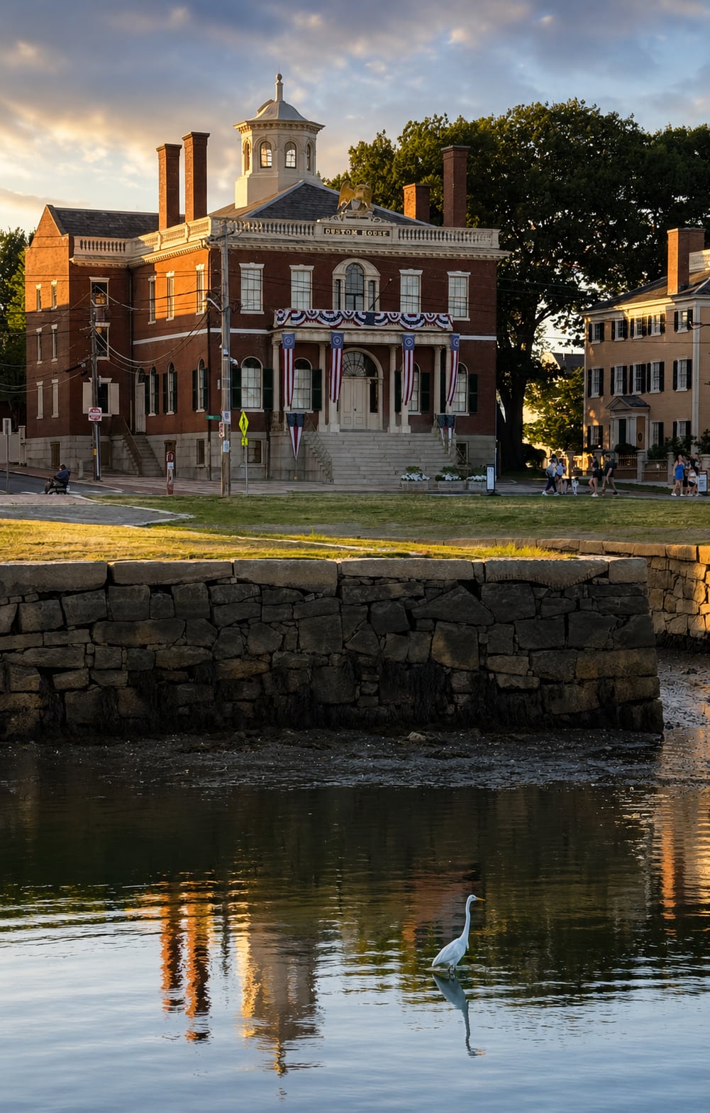 Salem's brick Custom House with its gilded eagle reflected in the tidal water at sunset, a great egret wading in the foreground