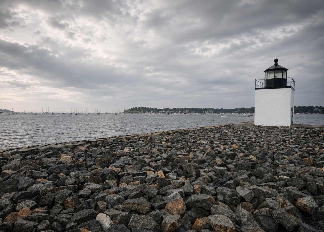 Derby Wharf Light, a small white lighthouse, at the end of a rocky breakwater on Salem Harbor under overcast skies, Salem MA