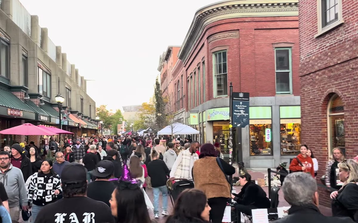 The Essex Street pedestrian mall packed shoulder to shoulder with costumed crowds on a Haunted Happenings Saturday in October, brick storefronts and vendor tents stretching ahead toward the Peabody Essex Museum