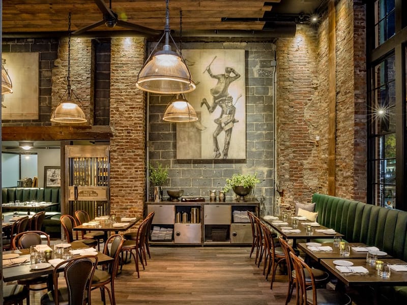 The dining room at Ledger Restaurant in Salem, MA — exposed brick walls, industrial pendant lights, and set tables