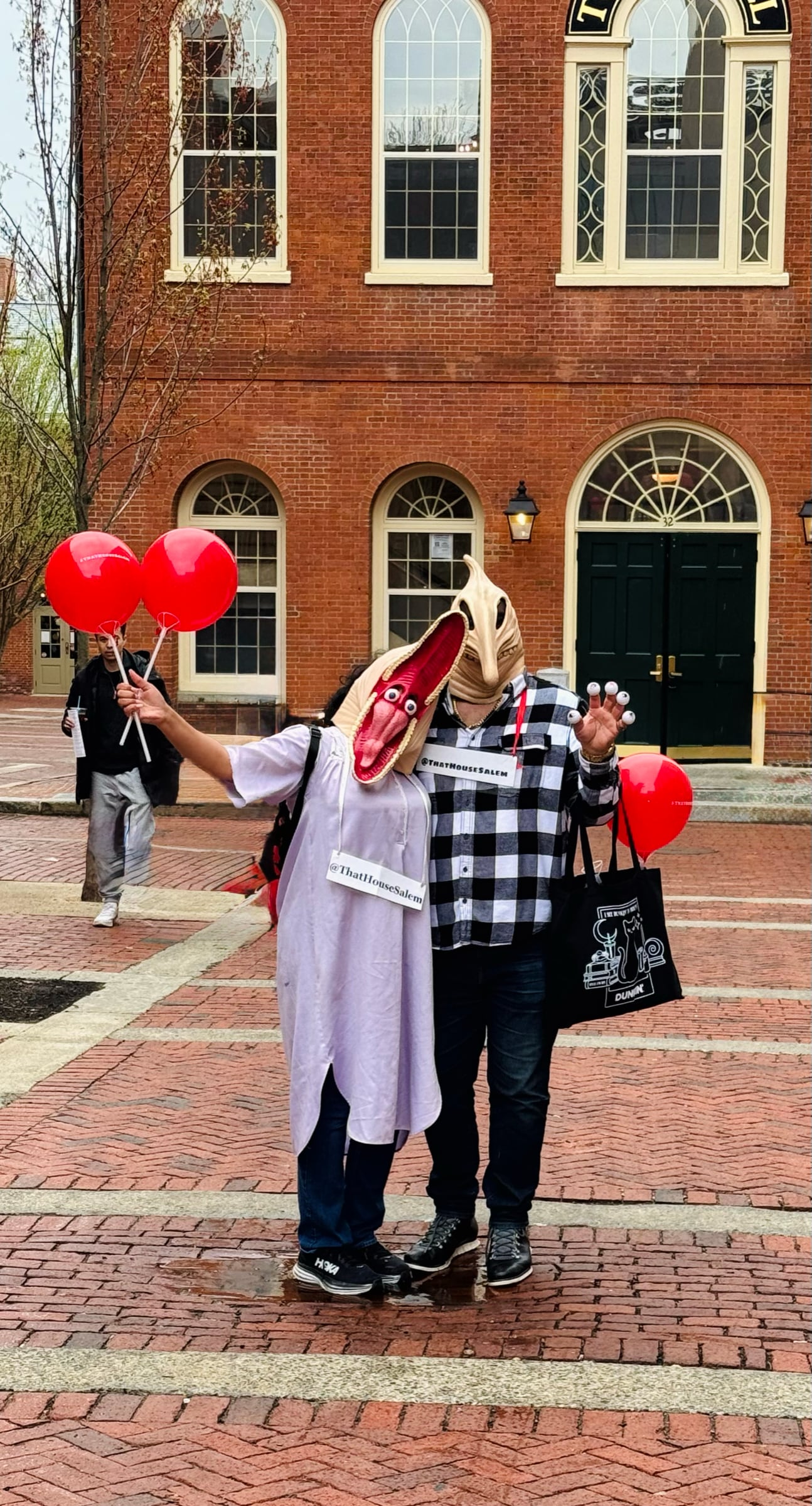 Halloween revelers with masks and balloons on Essex Street pedestrian mall in Salem MA