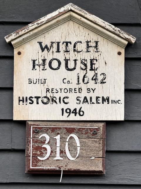 A weathered wooden plaque reading “Witch House, built ca. 1642, restored by Historic Salem Inc. 1946” above the house number 310, mounted on black clapboard
