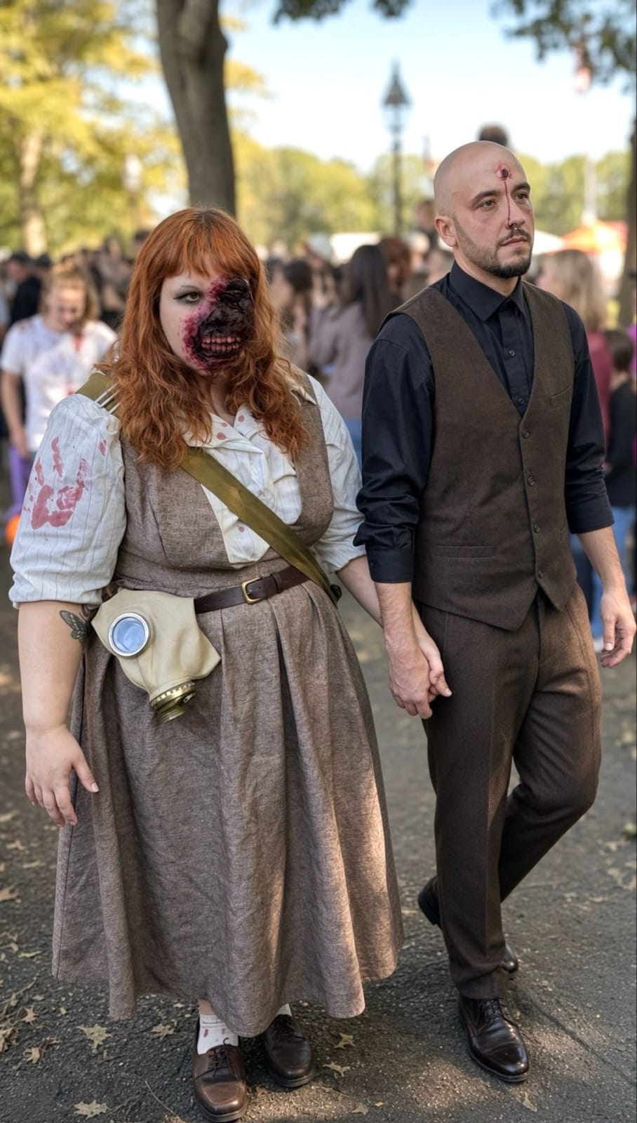A zombie couple walking hand in hand: a red-haired woman in a vintage dress with a gas mask bag and half her face rotted away, and a bald man in a vest with a wound on his forehead, on Salem Common